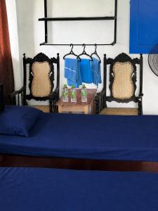 a bedroom with a bed with blue sheets and two chairs at Coca Cola Hostel Malabe in Malabe
