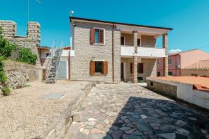 a house with a stone driveway in front of it at De Addis Guest House in Aggius