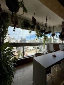 a room with a table and a large window with plants at Apartamento Praia da Costa in Vila Velha