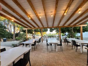 a patio with tables and chairs under a wooden ceiling at A casa di Raf in Torre Lapillo