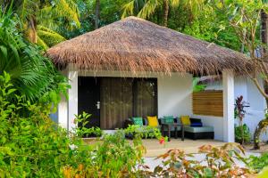 una casa con techo de paja y patio en Velassaru Maldives en South Male Atoll