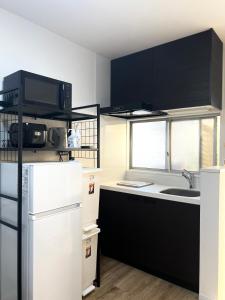a kitchen with a white refrigerator and a sink at Hotel Suite 24 in Warabi