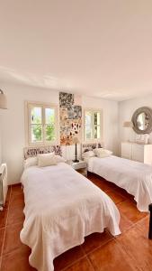 two beds in a white room with two windows at Villa in Nature with Yoga Room, Peace and Tranquility in Puigpunyent