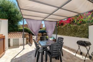 a patio with a table and chairs under a umbrella at San Teodoro Monti22 vicino spiaggia in San Teodoro