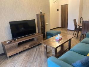 a living room with a flat screen tv and blue chairs at Cozy corner Komitas in Yerevan +4 photos