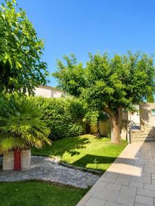 a garden with two trees and a sidewalk at Villa Victoire au coeur de la Provence in Venelles