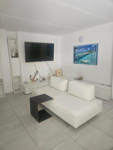 a white living room with a white couch and a tv at Domus cinque in Borghetto Santo Spirito