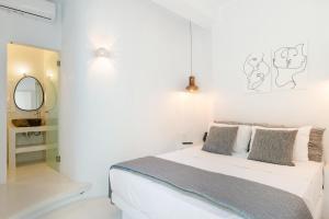 a white bedroom with a bed and a mirror at Edem Garden Suite in Andros