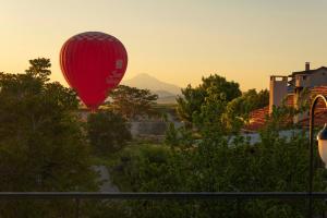 a red hot air balloon flying over a village at Cappadocia Golden Elite in Uçhisar