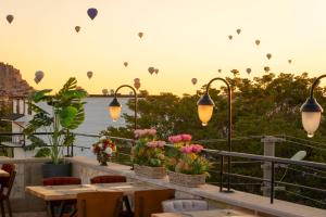 a balcony with tables and chairs and hot air balloons at Cappadocia Golden Elite in Uçhisar