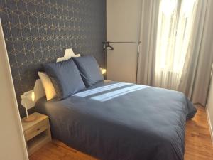 a bedroom with a bed with blue sheets and a window at Kergoat in Carhaix-Plouguer