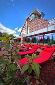a row of red chairs in front of a building at Hotel Piatra Mare in Poiana Brasov +175 photos