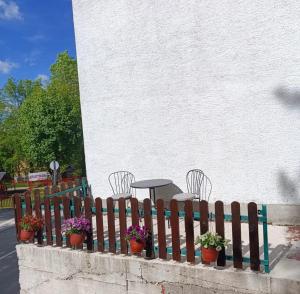 a wooden fence with chairs and a table and flowers at Apartman Mila in Žabljak