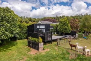 a black house with a deck and some animals at Fig Cottage in New Plymouth