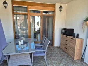 a dining room with a glass table and a television at Eve Santa Marina Studios - sea, pools, relax in Sozopol