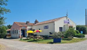 a house with a picnic table and two umbrellas at Camping de la Rive in Notre-Dame-de-Monts