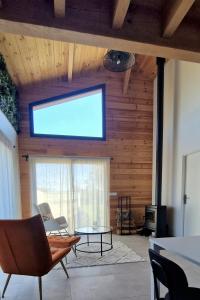 a living room with a large window and a table at Pinéa Lodge - Chalet Authentique en Pin des Landes in Saint-Yaguen