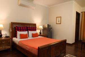 a bedroom with a bed with orange sheets and a refrigerator at Perch Arbor Suites in Gurgaon