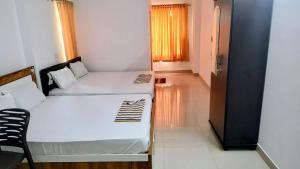 a small room with two beds and a window at Krisna vykundam in Guruvāyūr