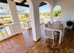 a dining room with a table and chairs and the ocean at Villa KAKABA in Son Bou