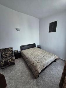 a bedroom with a bed and a chair in it at Къща за гости Бавария in Ravda