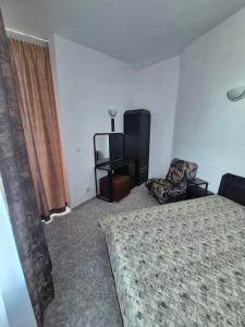 a bedroom with a bed and a chair and a window at Къща за гости Бавария in Ravda