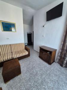 a living room with a couch and a tv at Къща за гости Бавария in Ravda +7 photos