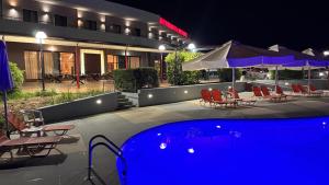 a hotel pool with chairs and umbrellas at night at Achillio Hotel in Komotini