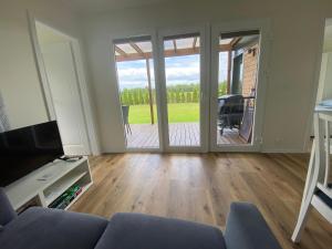 a living room with a couch and a sliding glass door at Cztery Domki in Stare Kiejkuty