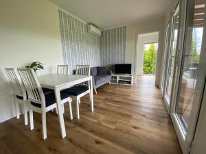 a dining room with a white table and chairs at Cztery Domki in Stare Kiejkuty