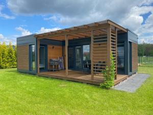 a modular house with a deck in a yard at Cztery Domki in Stare Kiejkuty