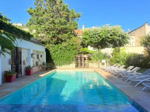a swimming pool with chairs and a house at Hôtel La Suite in Villeneuve-lès-Avignon