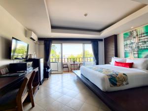 a bedroom with a large bed and a desk with a television at Wild Orchid Krabi in Ao Nam Mao