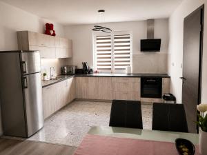 a kitchen with a stainless steel refrigerator and black chairs at Móra Apartman in Pécs