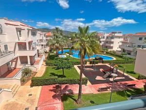 an apartment with a pool and palm trees and buildings at Apartamentos Las Arenas 3000 in Alcossebre