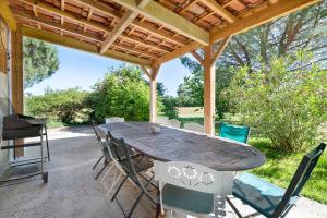 a wooden table and chairs under a wooden pergola at Domaine De Bellerose in Cadeillan