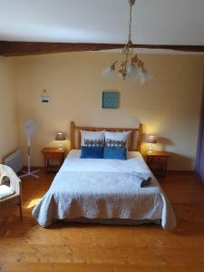 a bedroom with a large bed with blue pillows at La Grange Fleurie in Tramayes