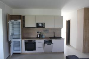 a kitchen with white cabinets and an open refrigerator at Apartmány Nitrianska osada in Bánov