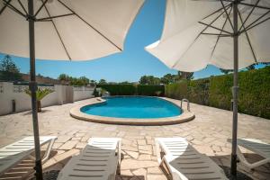 a swimming pool with two chairs and an umbrella at Villa Mª José in Benicarló