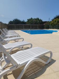 a row of white lounge chairs next to a swimming pool at Camping de la Rive in Notre-Dame-de-Monts
