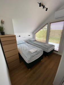 a bedroom with two beds and a dresser and two windows at Domki Osada Wałpusz dom bliźniak in Zielonken