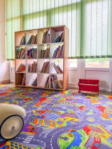 a library with a book shelf and a red bench on a rug at Mojo Resort in Eforie Sud