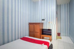 a bedroom with a bed and a flat screen tv at RedDoorz at Kuning GH Jatinangor in Sayang +8 photos