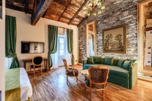 a living room with a green couch and a stone wall at Aurum Collection - Como Suites in Como