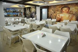 a restaurant with white tables and chairs and a giant head on the wall at Aditya Homes Gachibowli in Hyderabad