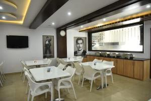 a restaurant with white tables and chairs and a television at Aditya Homes Gachibowli in Hyderabad