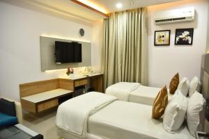 a hotel room with two beds and a television at Aditya Homes Gachibowli in Hyderabad