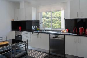 a kitchen with white cabinets and a sink and a window at Apartamento Luar in Ribeira Brava
