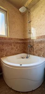 a white bath tub in a bathroom with a window at Little house Kazbegi in Kazbegi +43 photos
