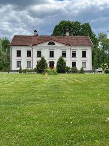 a large white house with a large grass field at Flishult gård in Vetlanda